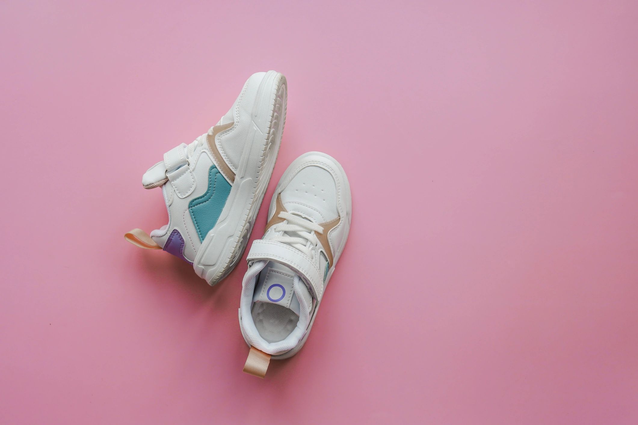 White children's sneakers on a pink background