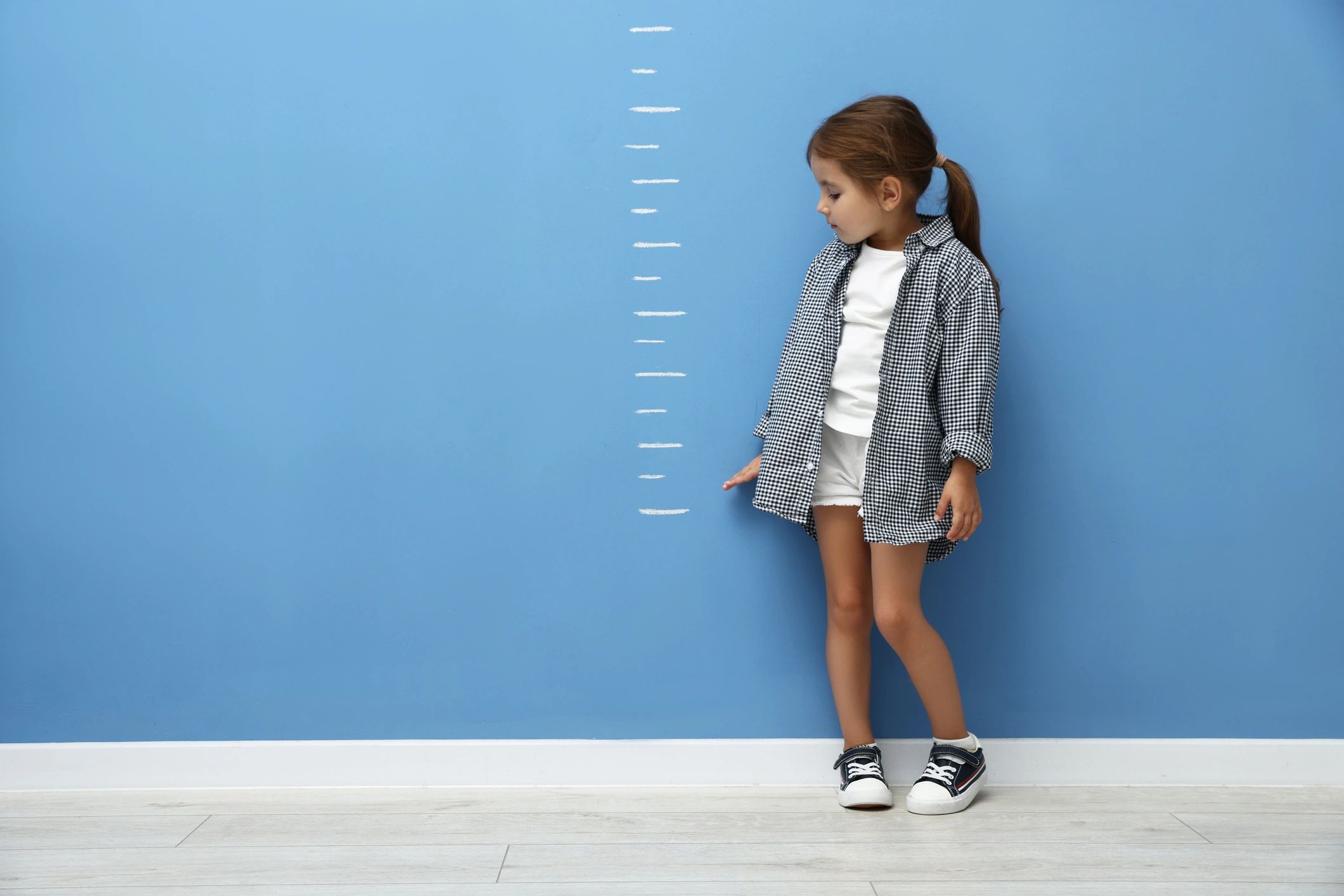 Little girl measuring her height for clothing size guidance